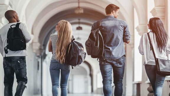 People walking in an arched hallway with backpacks