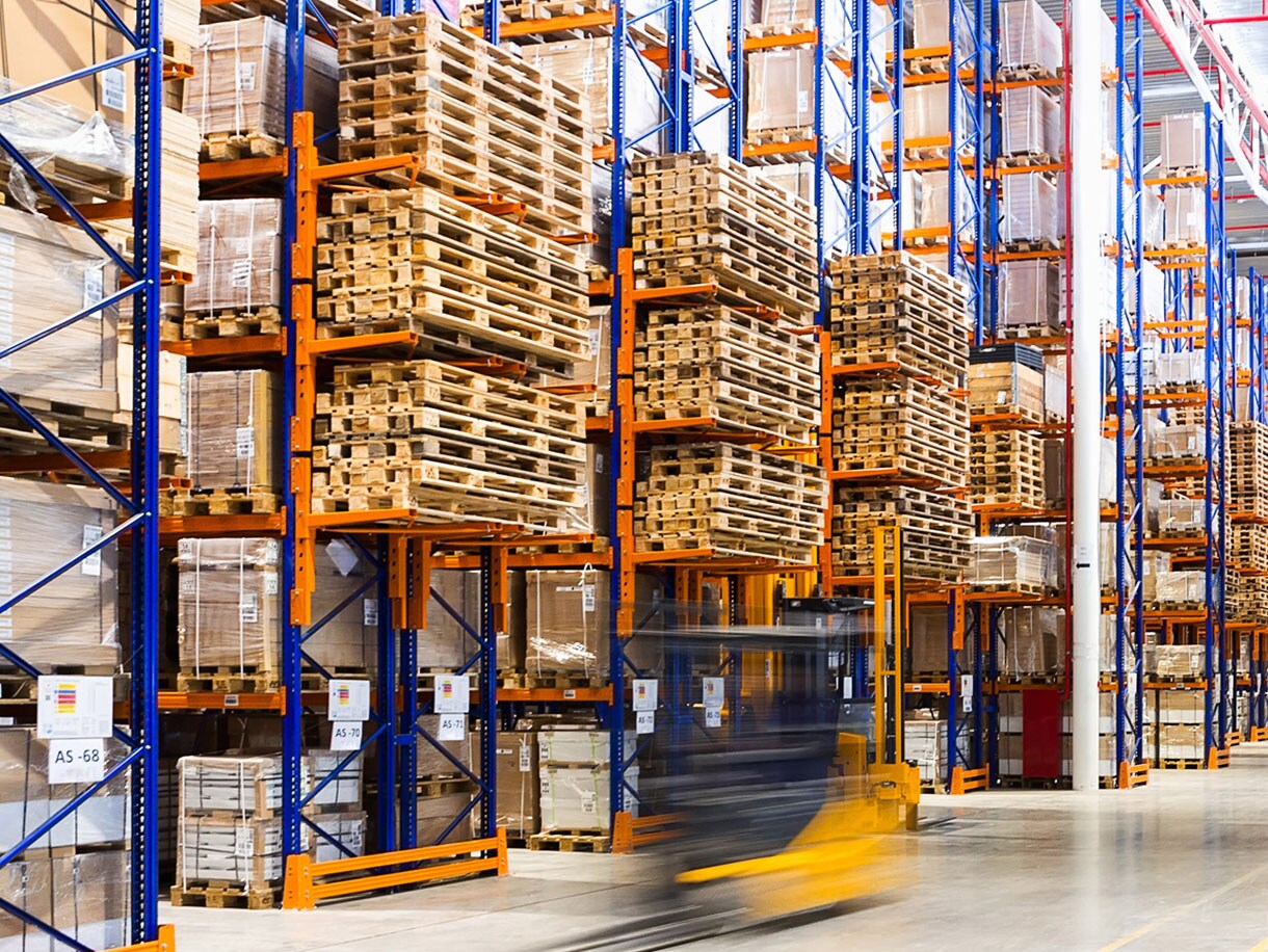 Motion-blur shot of a forklift moving in a warehouse in front of a huge rack of goods