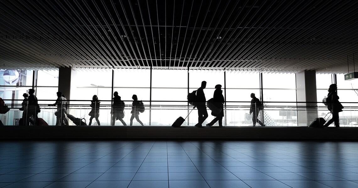 People with luggage walking across a moving walkway in an airport