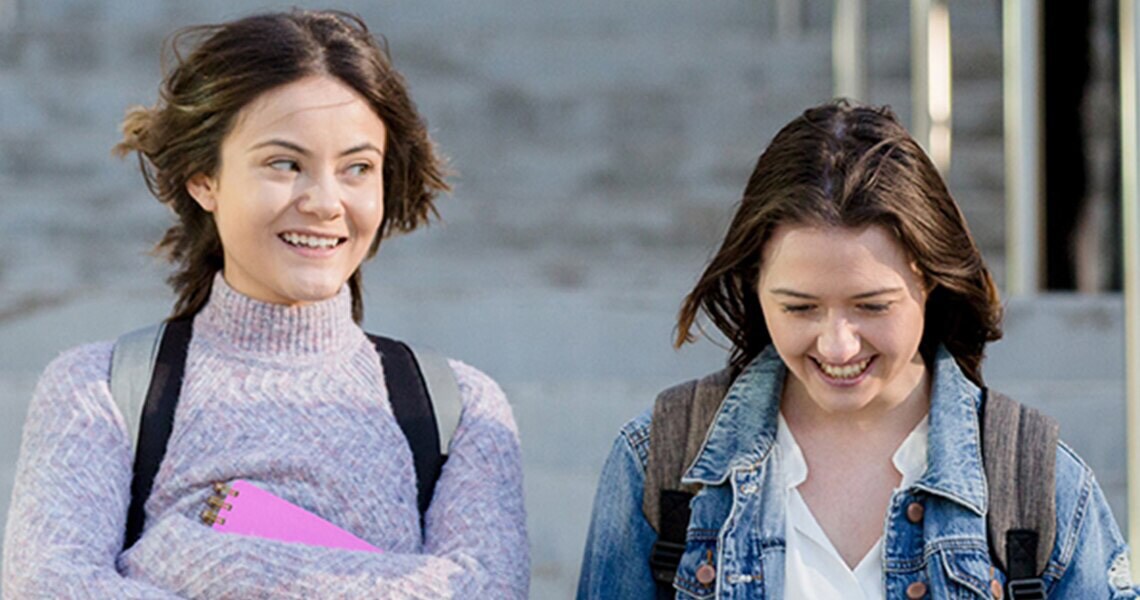 Two female students smiling and walking