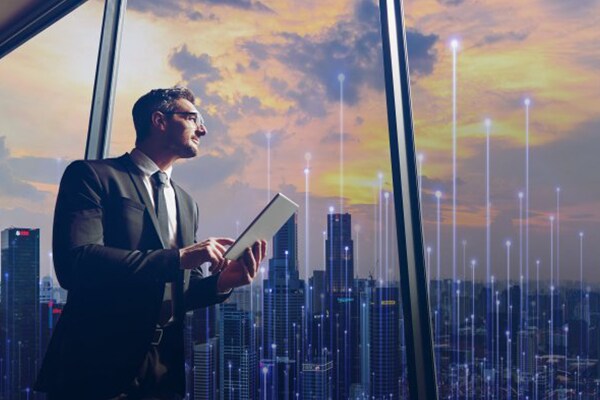 Man in formals working on a tablet and looking at a cityscape outside the window