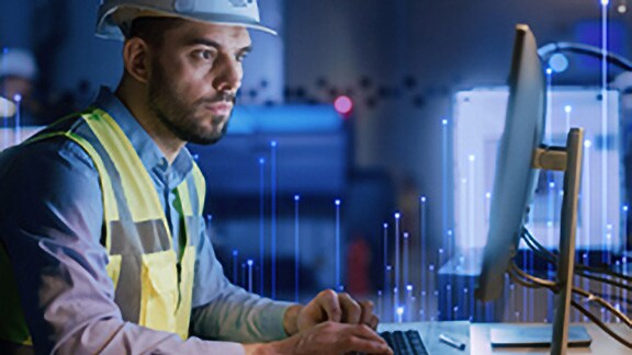 Técnico da Johnson Controls utilizando computador de escritório, sobreposto com um gráfico de nós de transmissão ao fundo