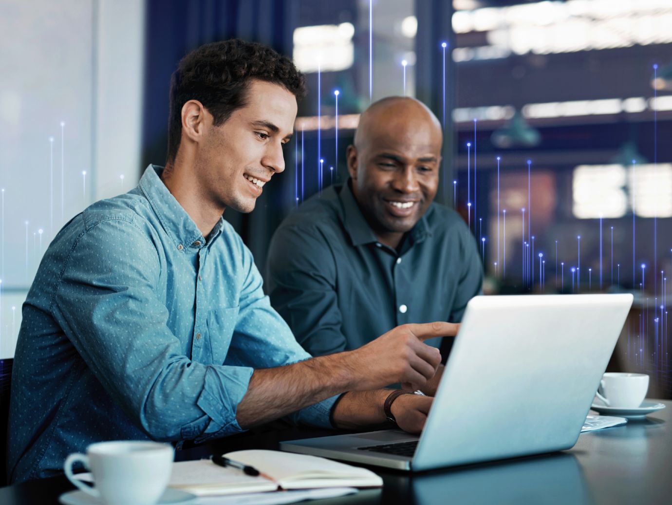 Dois colaboradores conversam diante de um notebook