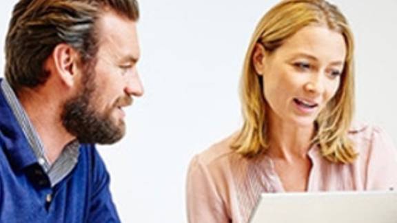 A man and a woman having a conversation while working on a laptop