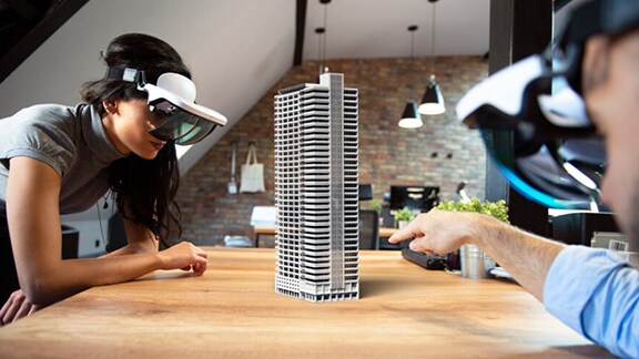 Duas pessoas explorando a vista de um edifício com a ajuda de realidade virtual