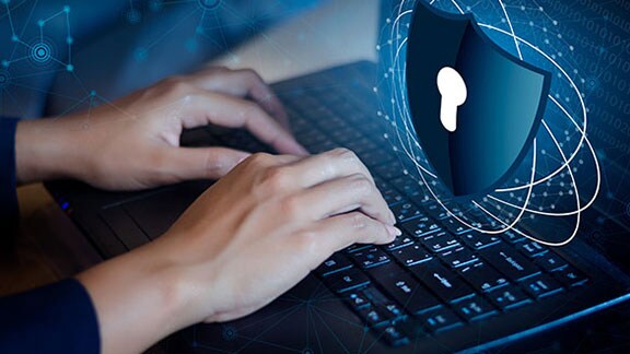 Close-up of a person working on a laptop, with a graphic of a keyhole on a shield, depicting cybersecurity, overlaid on top