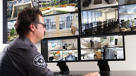 Um segurança examinando um monitor exibindo imagens de vigilância por vídeo