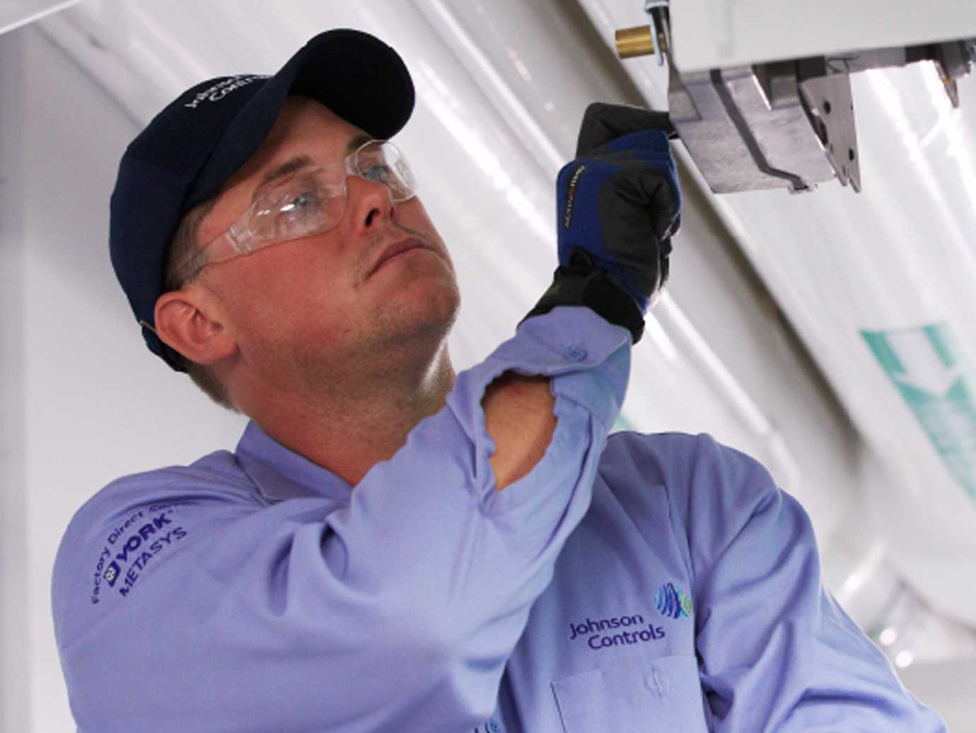 A Johnson Controls mechanic conducting a factory inspection on an HVAC device