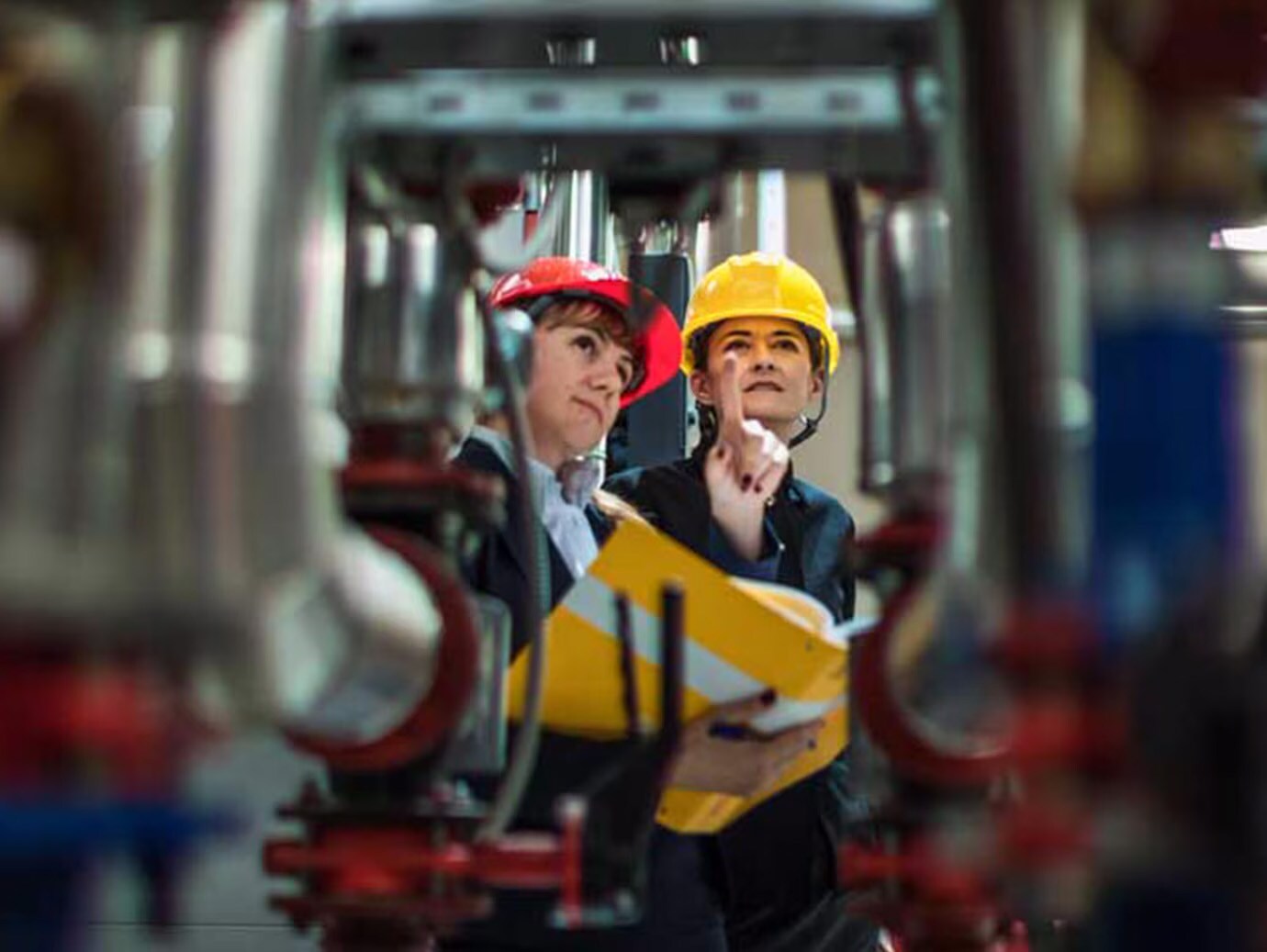 Two female mechanics examining a series of pipes