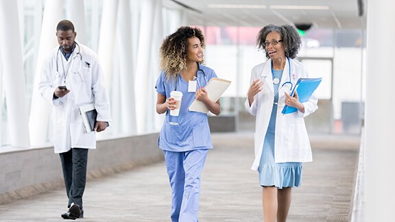 Doctors and nurses conversing and walking along a passage in a hospital