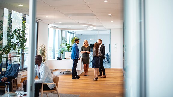 A group of colleagues in conversation at an office lobby